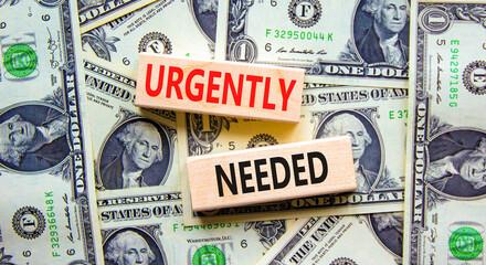 Urgently needed symbol. Concept words Urgently needed on wooden blocks on a beautiful background from dollar bills. Business and urgently needed concept. Copy space.