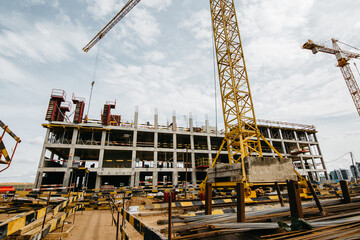 cranes at the construction site of stylish houses against the blue sky