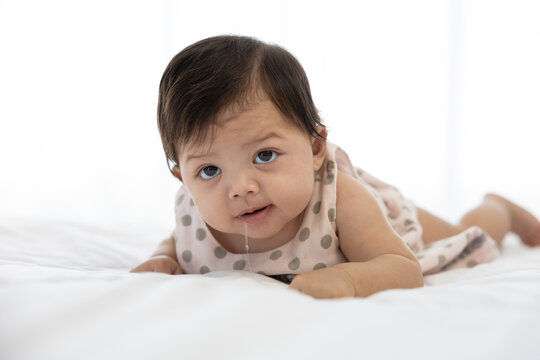 cute baby crawling on bed and drooling from mouth