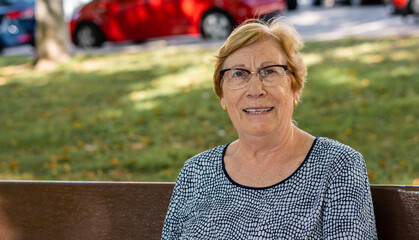 Portrait smiling caucasian elderly woman sitting in a park. 