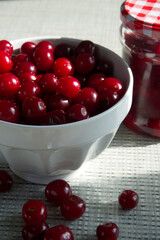 Cherries and a jar of jam on background and fresh fruits on the table, closeup