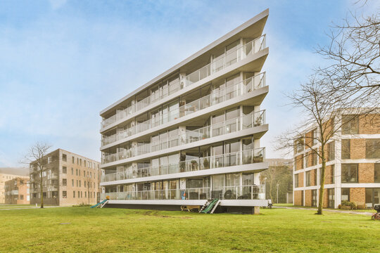 Contemporary building facades near green grass under cloudy sky
