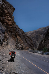 Motorcycle on mountain road in Himalayas among high stone cliffs
