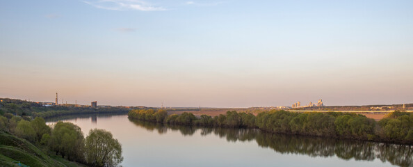 Evening landscape. Cloudy May day. Clouds are reflected in the lake. Peaceful landscape on the banks of the reservoir. Relax in nature.