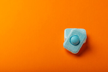 Water softener tablets on orange background, flat lay. Space for text.Capsules for washing machines...