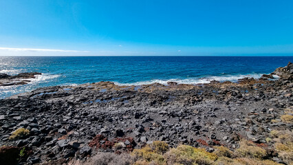 Fototapeta na wymiar Panoramic view on black sand beach Playa de San Blas near Los Abrigos, Tenerife, Canary Islands, Spain, Europe, EU. Coastline of the Atlantic Ocean. Crystal blue lagoon with no people. Vacation
