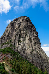 Scenic view on massive volcanic rock formation Roque de Agando in Garajonay National Park on La Gomera, Canary Islands, Spain, Europe. Lava cone of an old volcano. Hiking trail on sunny day in summer
