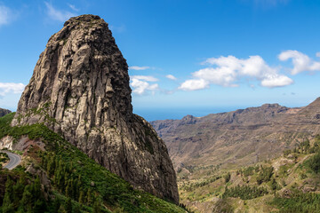 Fototapeta na wymiar Scenic view on massive volcanic rock formation Roque de Agando in Garajonay National Park on La Gomera, Canary Islands, Spain, Europe. Lava cone of an old volcano. Hiking trail on sunny day in summer