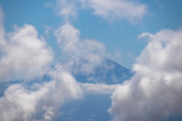 Scenic view on the cloud covered volcano mountain peak Pico del Teide on Tenerife seen from La Gomera, Canary Islands, Spain, Europe. Mystical magical atmosphere on hiking trail to Roque de Agando