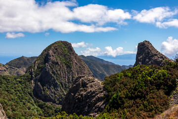 Obraz premium Massive volcanic rock formations in Garajonay National Park seen from Roque de Agando, La Gomera, Canary Islands, Spain, Europe. Hiking trail over hills covered by forest and tropical fauna in summer