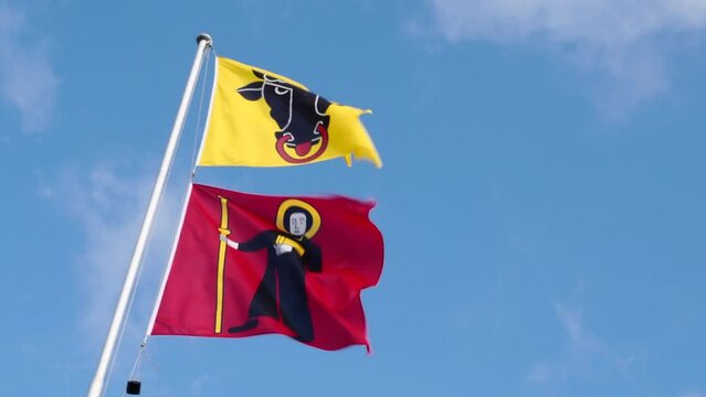 Klausenpass, Switzerland - June 2, 2022: Flags at the border of cantons Uri (yellow flag) and Glarus (red flag) at Klausenpass in Switzerland