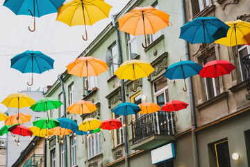 Fototapeta na wymiar Colorful umbrellas are installed between the cityâ€™s buildings. Colour. Colorful. Decoration. Decorative. District. Europe. Facility. Festive. Hang. Happiness. Installation. Installed. Landmark