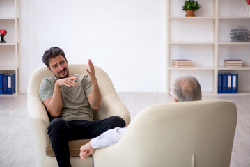 Young man visiting old psychologist