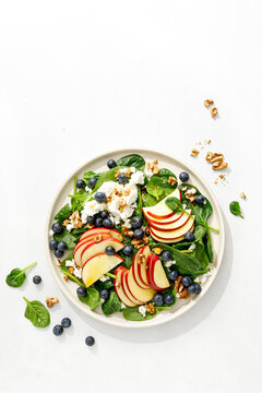 Apple and spinach fresh sweet fruit salad with blueberry, cheese cottage and walnuts, top view