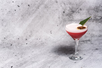 Beautiful red cocktail garnished with dried orange and green leaf on a concrete background. Long stem glass. Free space for your text