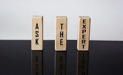 ASK THE EXPERT written on wooden blocks and black and white background with reflection