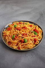 Homemade Spaghetti Pasta with Fresh Tomato Sauce on a Plate on a gray surface, side view. Close-up.