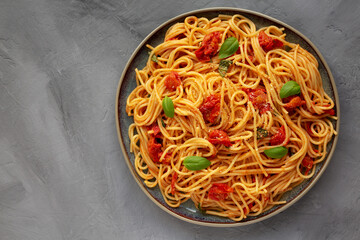 Homemade Spaghetti Pasta with Fresh Tomato Sauce on a Plate on a gray surface, top view. Flat lay, overhead, from above. Copy space.