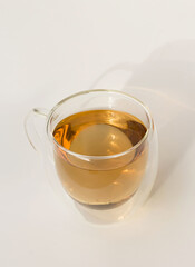 Herbal tea in a double-walled glass cup on a white table. Morning tea at sunrise