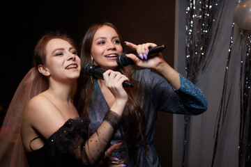 party, holidays, celebration, nightlife and people concept - happy young women singing karaoke in...