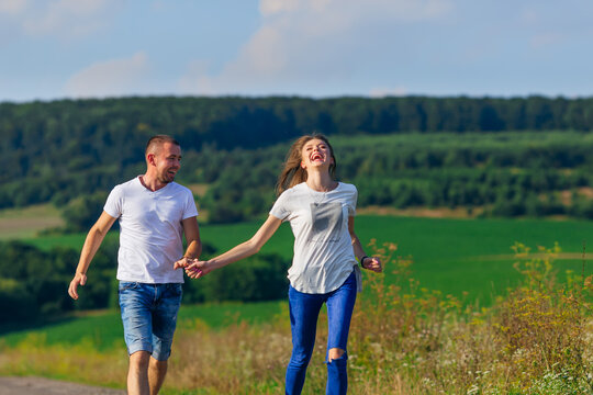 couple in casual clothes holding hands and running against fores