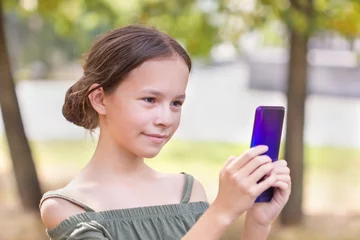 Abwaschbare Fototapete Süße Monster . Glückliches Mädchen, das auf ihrem Telefon aufpasst. Kind fotografiert sich selbst