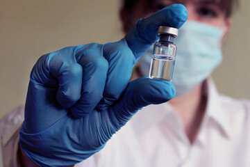 A female doctor holds a vial of vaccine in her hand. Hand close up.