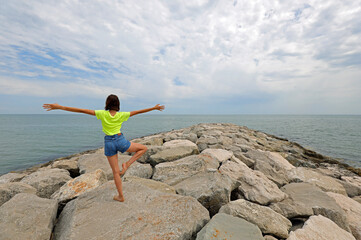 girl does rhythmic gymnastics exercises on the rocks by the sea