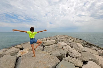 Fotobehang girl does rhythmic gymnastics exercises on the rocks by the sea © ChiccoDodiFC