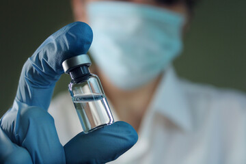 A female doctor holds a vial of vaccine in her hand. Hand close up.