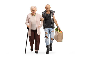 Man holding a senior woman under arm and carrying her grocery bag