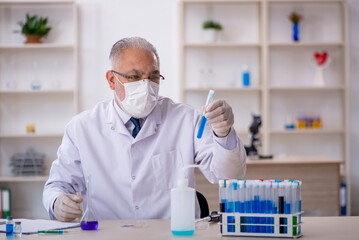 Old male chemist working at the lab - obrazy, fototapety, plakaty