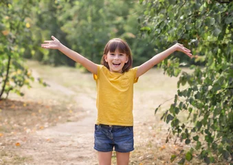 Foto op Plexiglas Jong kind armen opgewekt naar de hemel, vrijheid vieren. Positieve kinderen emoties. Gratis lachend meisje in zomer bos genieten van de natuur. Gelukkig leven concept © Albert Ziganshin