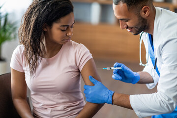Black lady getting vaccinated against coronavirus at clinic - obrazy, fototapety, plakaty