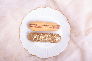 Beautiful golden colored eclairs on plate, on lace background