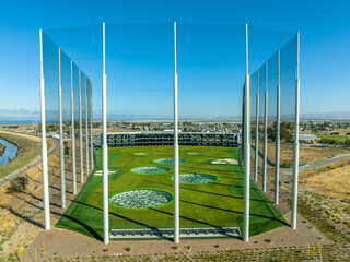 Aerial view of fenced golf driving range with high tech targets, rows of air conditioned hitting...