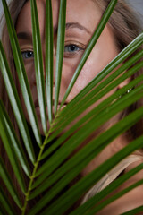 Alluring in good shape bewitching female model over 20s in sandy clothes cuddling the fern leave...