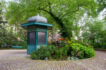 A small beautiful garden with a flower garden and a wooden kiosk between the tomb of Napoleon...