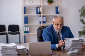 Fototapeta premium Old male employee and too much work in the office