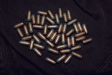 Many .45 ACP cartridges on a black denim background