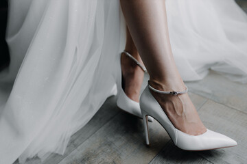 Wedding white shoes on the feet of the bride on a gray background. Up close