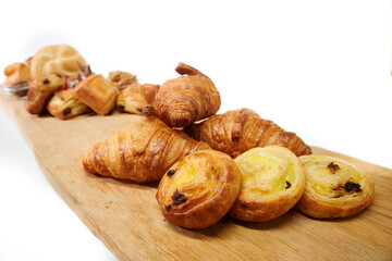 A wooden board with various types of pastries and toppings on a white isolated background