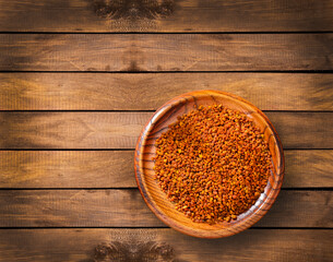 Organic bee pollen grains in the wooden bowl