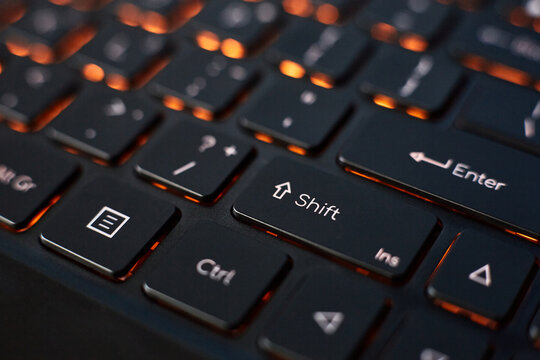 Close-up of a laptop keyboard with orange backlight.