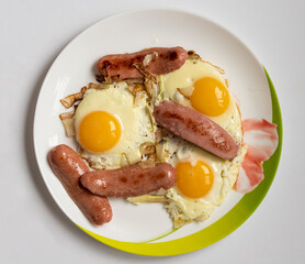 fried fried eggs with sausages and onions on a white plate on a white table