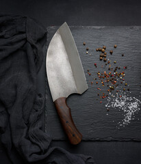 Large kitchen knife on a black graphite board and spices