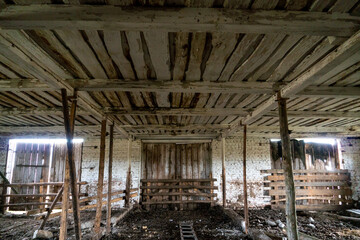 Abandoned ruined barn cowshed inside view. The old abandoned barn with the remains of feeders. barn from inside with low light