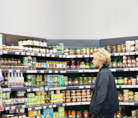 Young man shopping in supermarket, reading product information