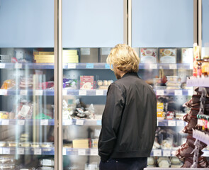  Man choosing frozen food from a supermarket freezer., reading product information