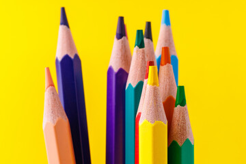 Colored pencils close-up with selective focus on the stylus and a blurred yellow background